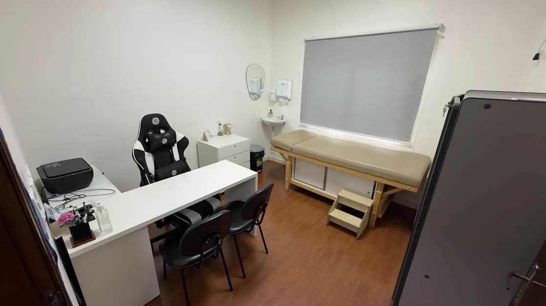 Consultório da clínica, com mesa de atendimento e maca de exame