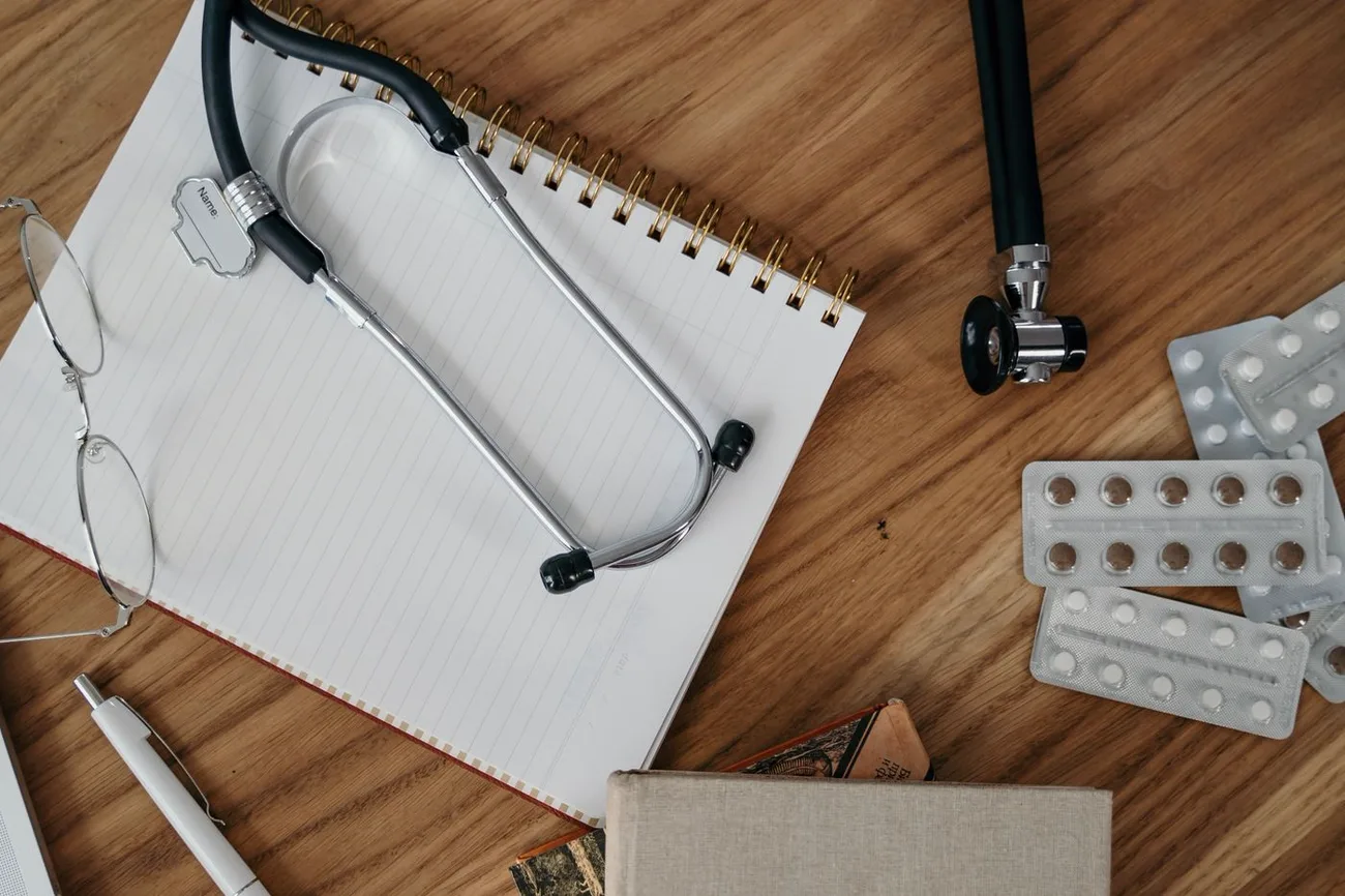 Estetoscópio, caderno e óculos sobre a mesa