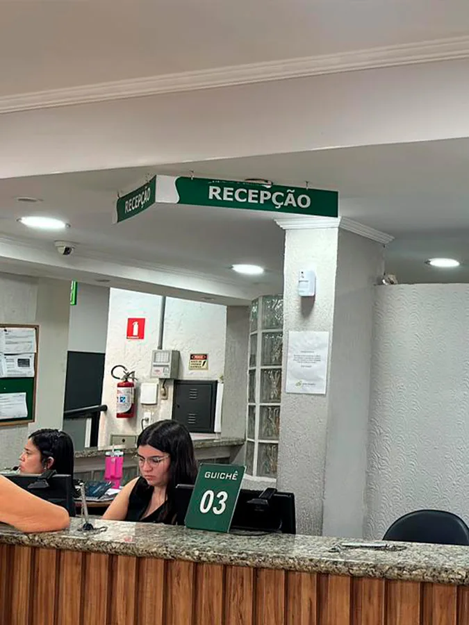 Balcão da recepção da clínica, com atendentes nos guichês