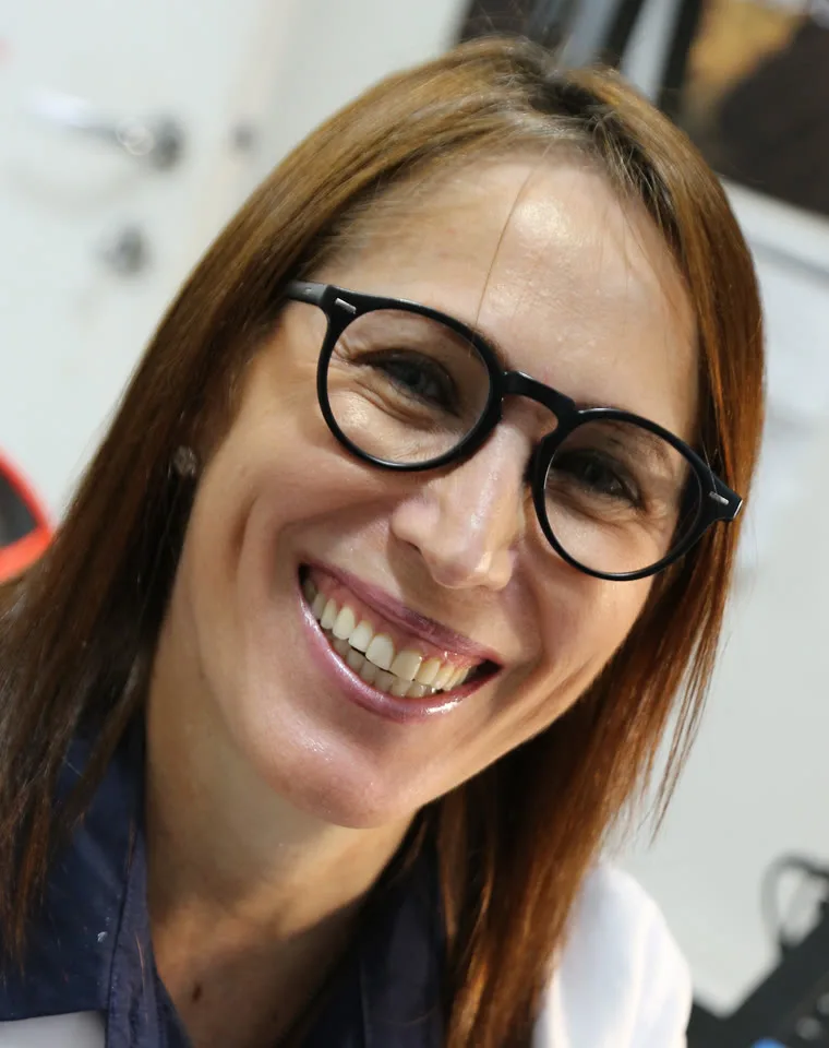 Dra. Bernardete de Freitas Dias, de jaleco branco, sorrindo no consultório