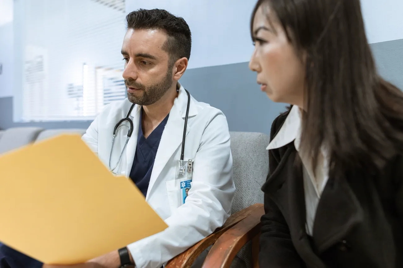 Médico revendo o prontuário ao lado da paciente